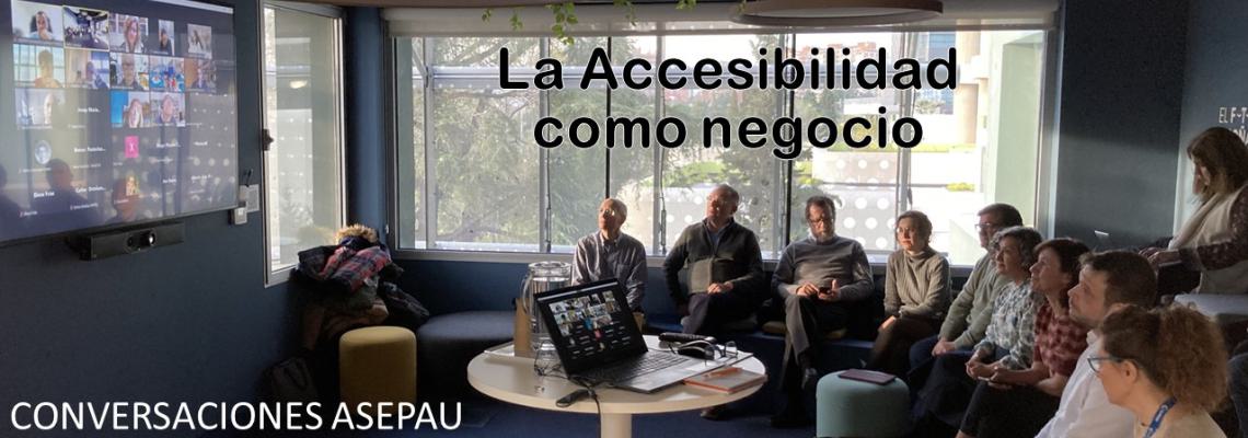 CONVERSACIONES ASEPAU: La Accesibilidad, oportunidad de negocio. Vista general de una sala con gente sentada en semicírculo frente a una gran pantalla con participantes en una videoconferencia