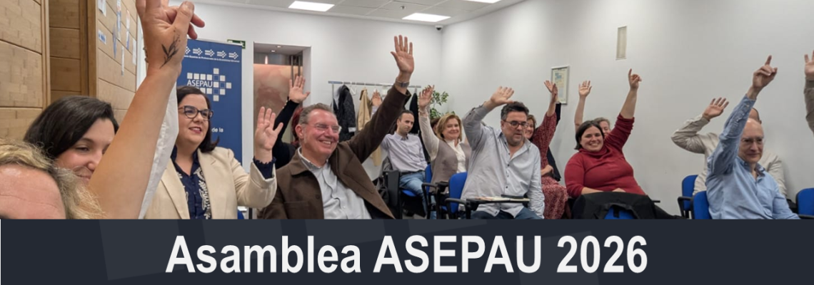 grupo de personas sentadas en una sala en varias filas con una mano levantada y sonriendo